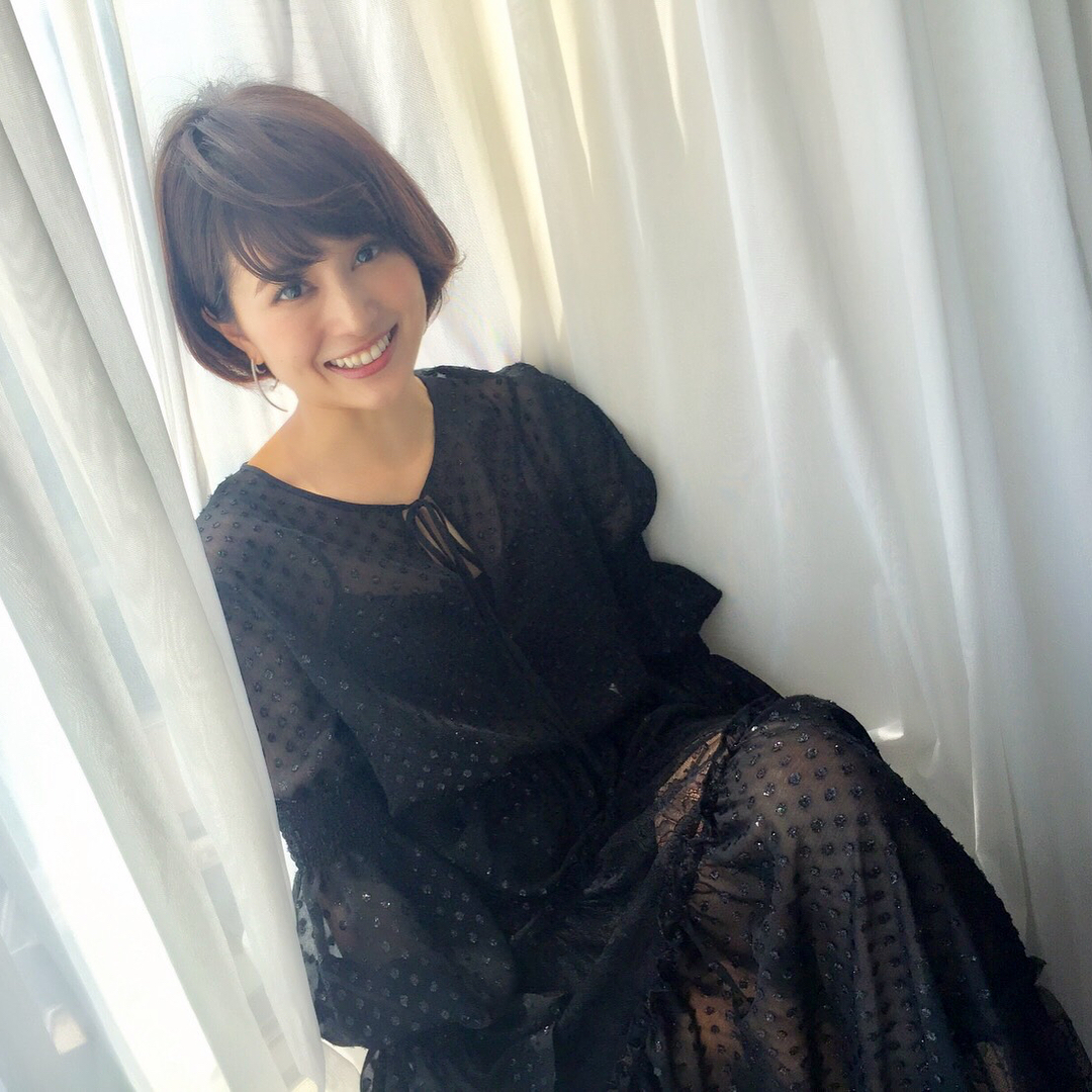 カーテンにもたれかかり笑顔の佐津川愛美さん。「キレイ」と「カワイイ」の両方を持ち合わせています。