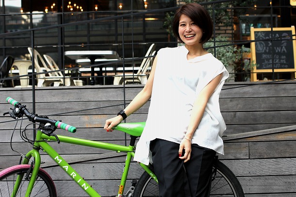 ホワイトのシャツでライムグリーンのシティバイクに乗る佐津川愛美さん。ナチュラルな笑顔に癒されます。