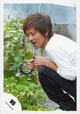 傘をさしてしゃがみ込む森田剛さん。何かを発見したような表情をしています。